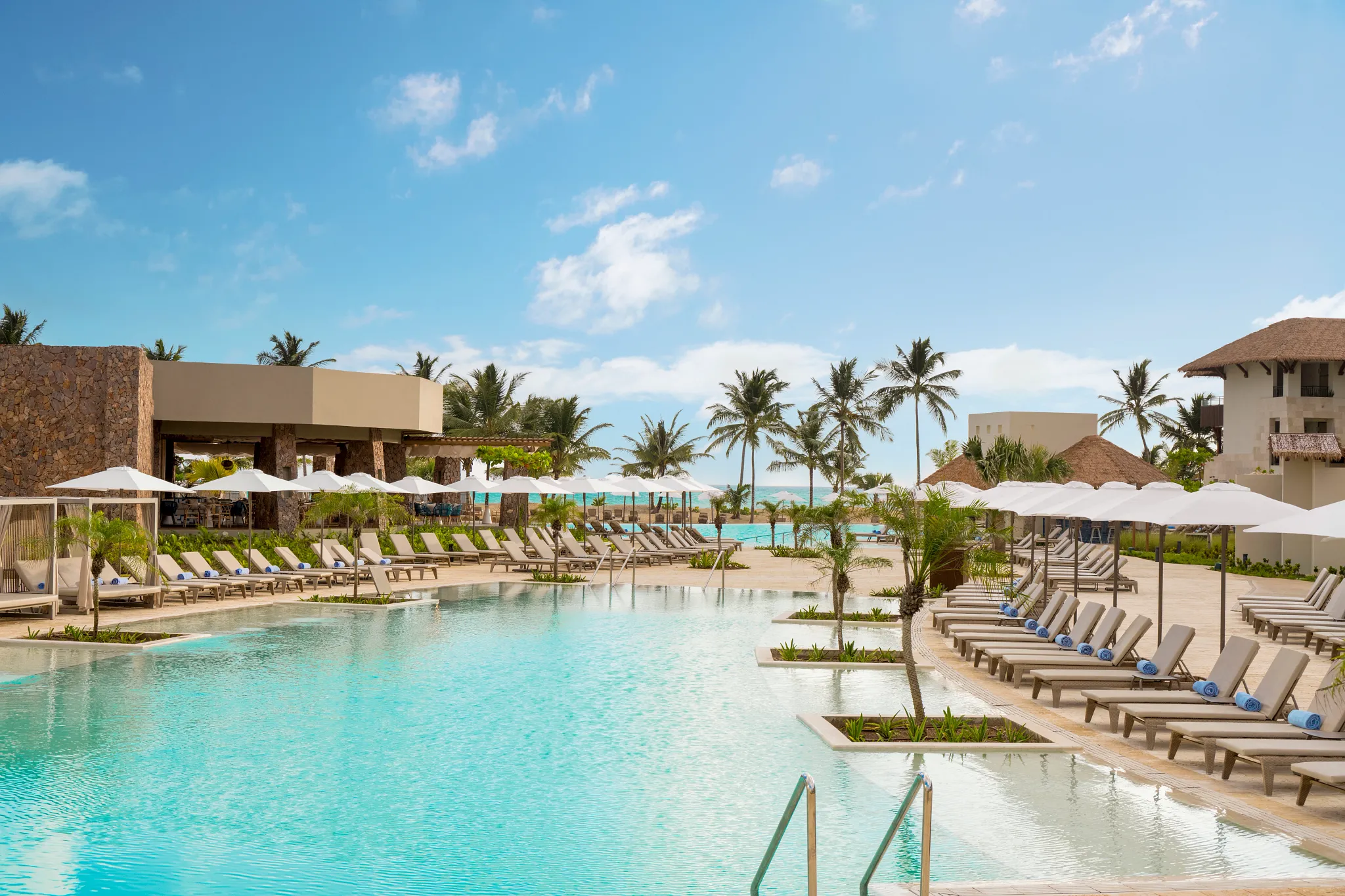 Peaceful resort pool lined with loungers and palm trees at Dreams Playa Esmeralda Resort & Spa.